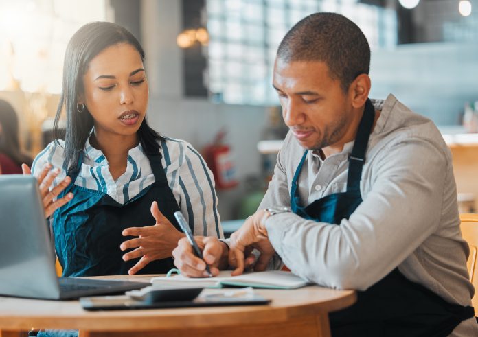 Small business owners discussing and managing cash flow in the cafe or coffee shop. Entrepreneurs having a financial discussion about the business finance strategy.